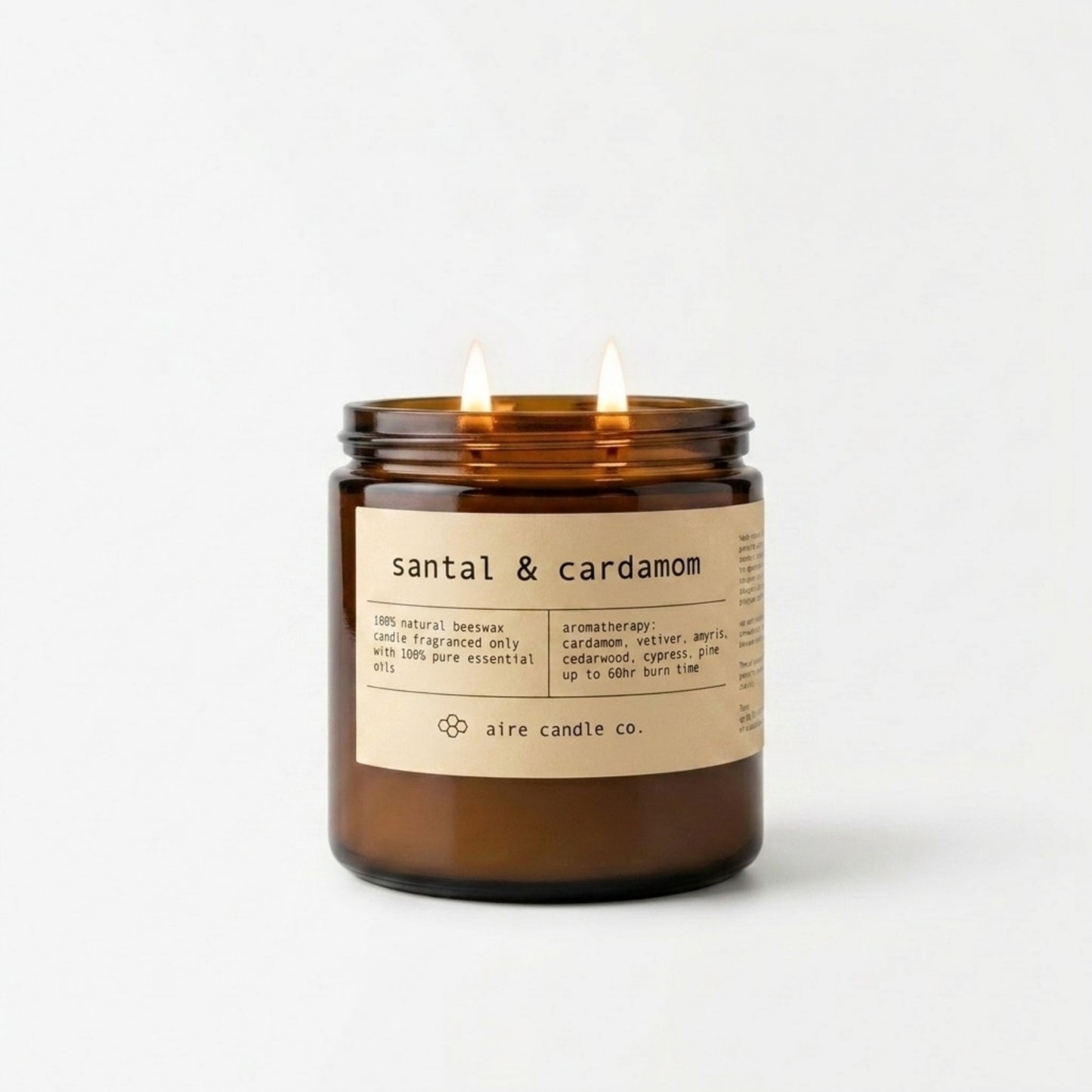 Santal & cardamom candle in an amber jar with a label on a white background
