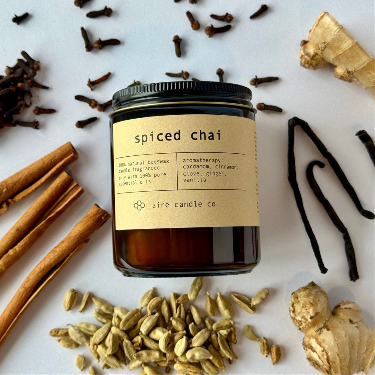 Spiced chai candle with spices and herbs on a white background