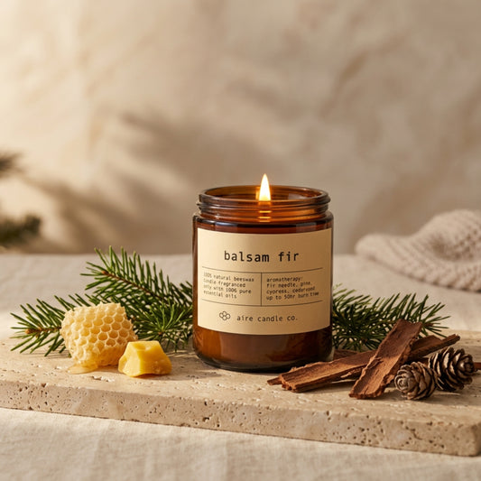 Balsam fir candle by aire candle co. with natural elements on a travertine surface