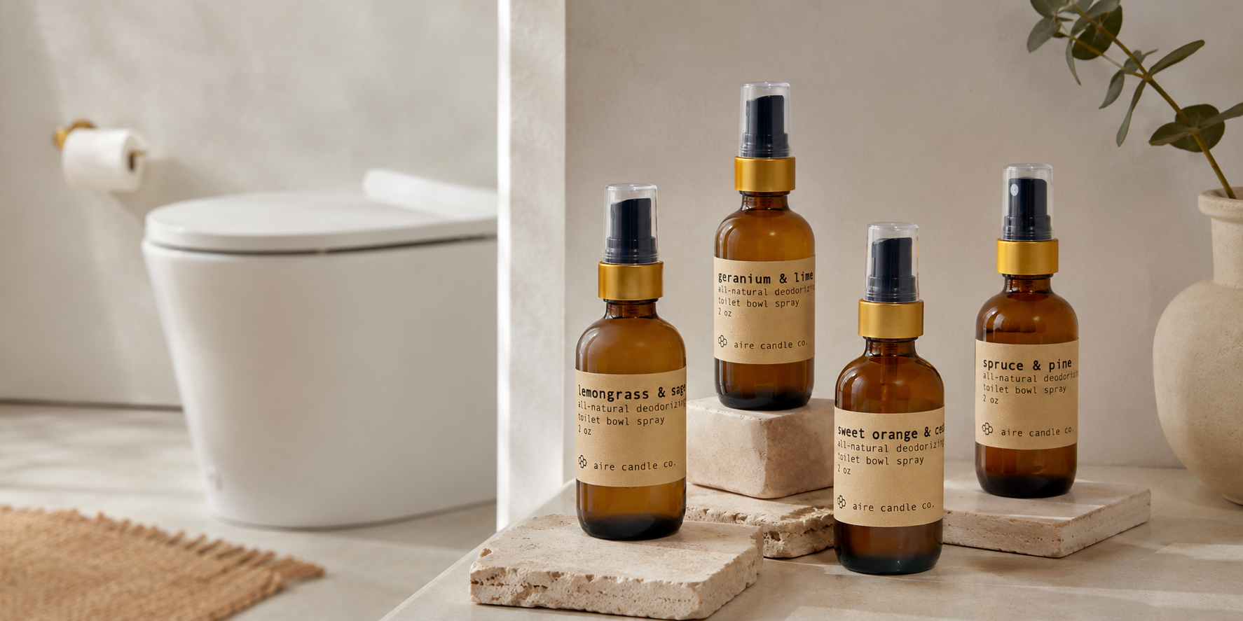aire candle co.'s deodorizing toilet bowl sprays featured in an organic style bathroom setting. The all-natural, essential oil fragranced sprays include sweet orange & clove, spruce & pine, geranium & lime and lemongrass & sage scents.
