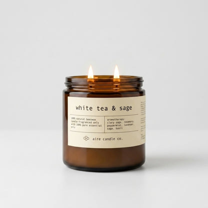 White tea & sage candle in an amber jar with a label on a light gray background