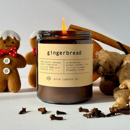 Gingerbread-themed candle with gingerbread men and spices on a light background