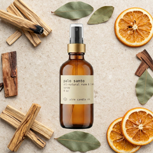 Aire Candle Co. Palo Santo Essential Oil Scented Room Spray Surrounded by Scent Notes of Palo Santo, Patchouli, Orange and Cedarwood Essential Oils.