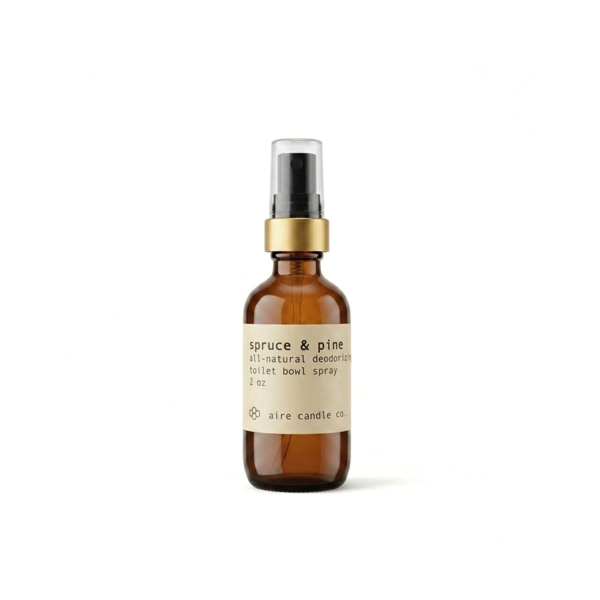 Aire Candle Co. Spruce & Pine Essential Oil Scented Deodorizing Toilet Bowl Spray Displayed Against a Clean White Background Housed in a Protective Amber Glass Bottle with a Gold Rim and Black Fine Mist Sprayer.