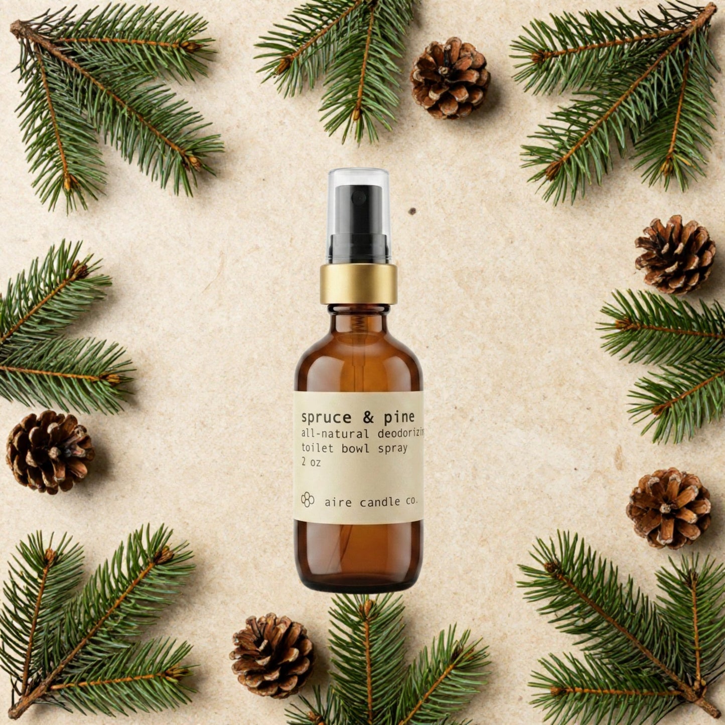 Aire Candle Co. Spruce & Pine Essential Oil Scented Deodorizing Toilet Bowl Spray Surrounded by Scent Notes of Spruce Needles and Pine Cones on a Travertine Surface.