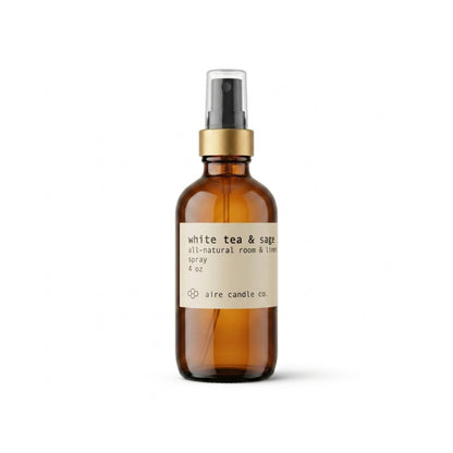 Aire Candle Co. White Tea & Sage Essential Oil Scented Room Spray Displayed Against a Clean White Background Housed in a Protective Amber Glass Bottle with a Gold Rim and Black Fine Mist Sprayer.