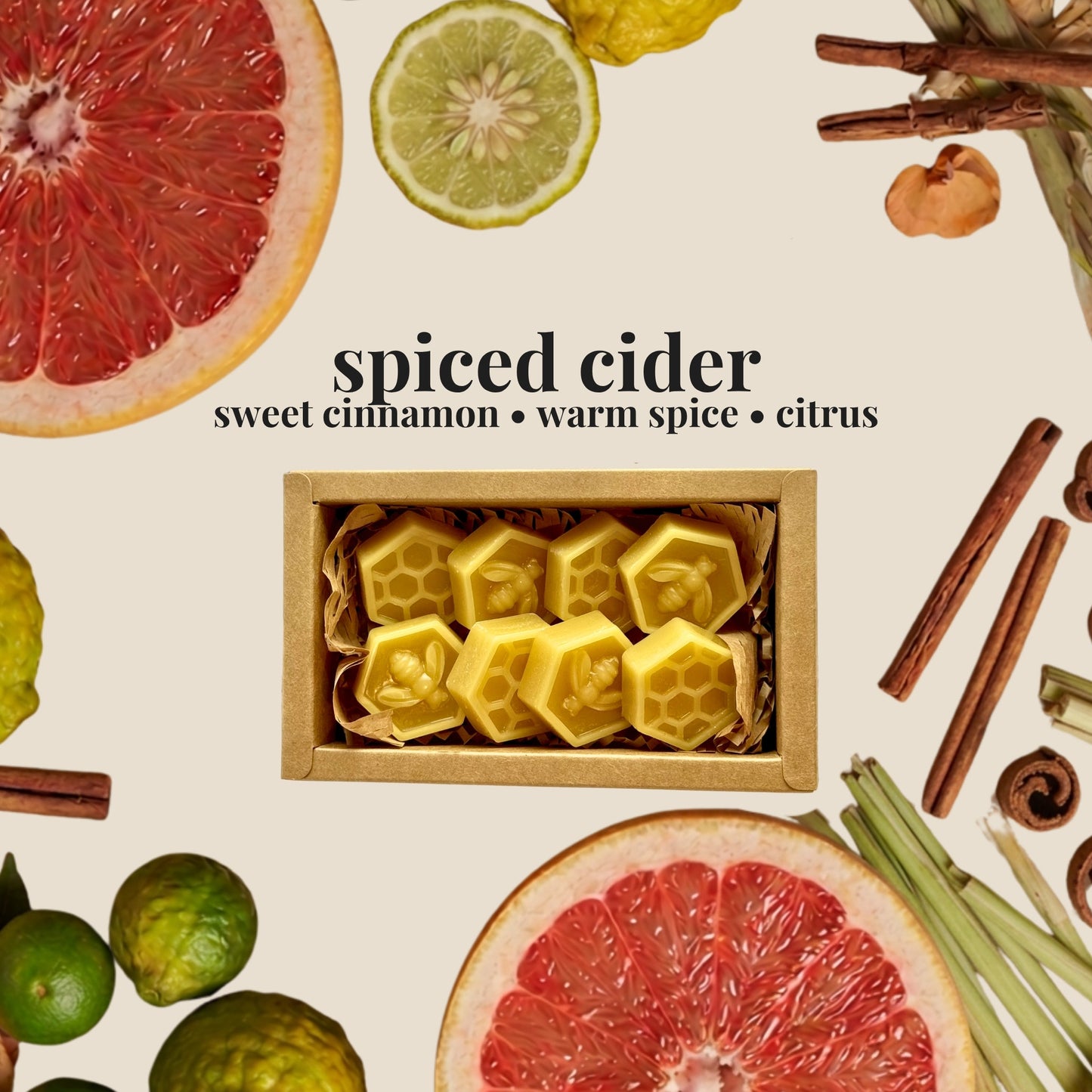 A styled flat-lay featuring a small kraft box of honeycomb-shaped yellow spiced cider wax melts, surrounded by citrus slices, cinnamon sticks, and lemongrass on a cream background. The text 'spiced cider' and 'sweet cinnamon • warm spice • citrus' appears above the box.