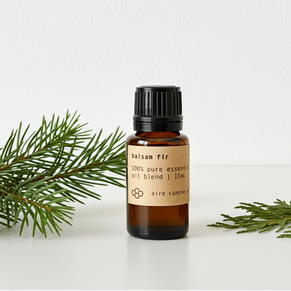Bottle of balsam fir essential oil blend with a sprig of fir on a white background