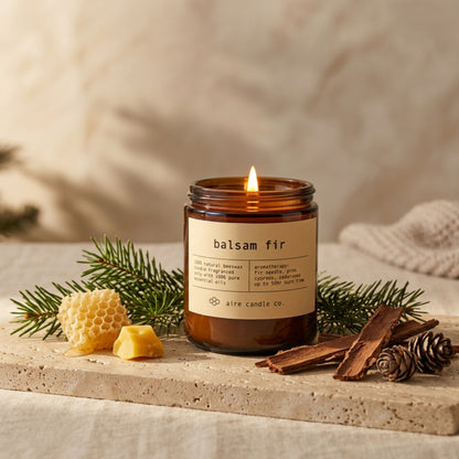 Balsam fir candle by aire candle co. with natural elements on a travertine surface