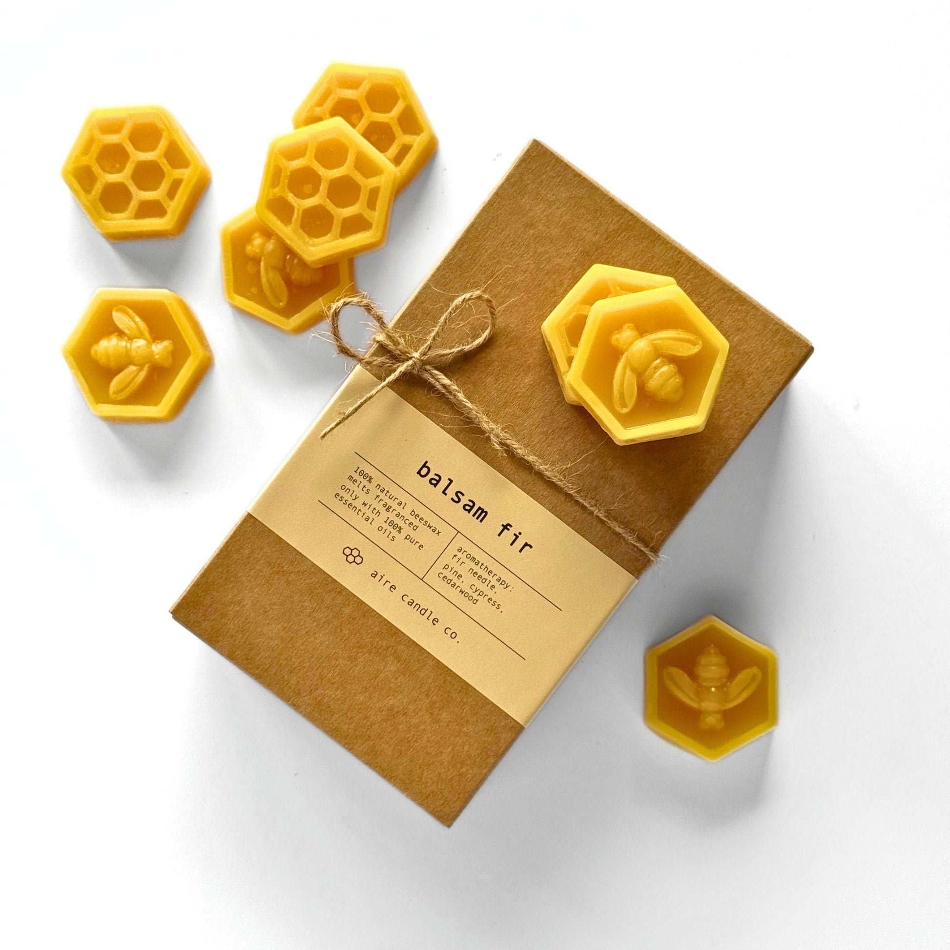 Box of balsam fir candles with honeycomb and bee designs on a white background