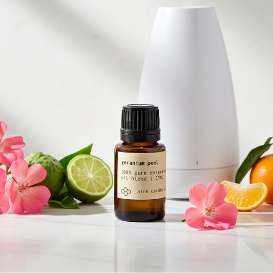 Essential oil bottle with geranium flowers, bergamot, and clementine on a white background