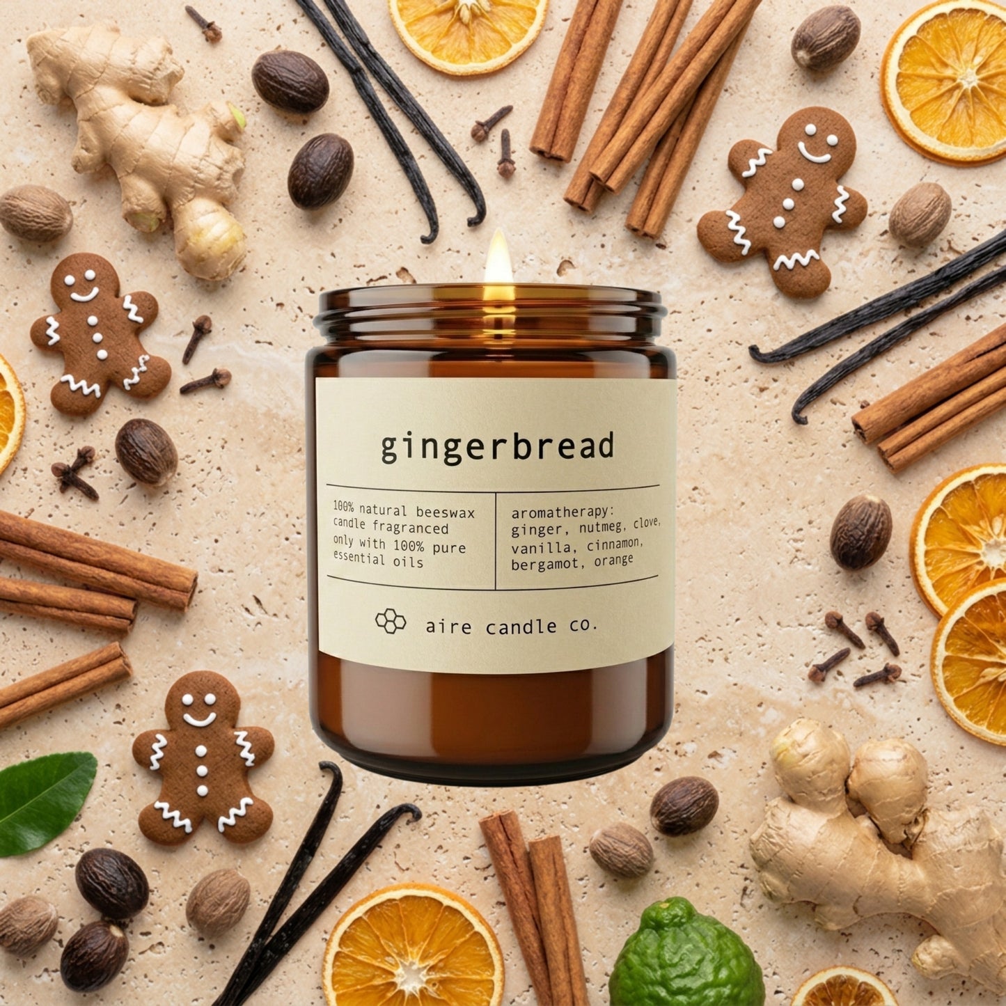 Gingerbread candle from aire candle co surrounded by ginger, gingerbread men, cinnamon, nutmeg, cloves, vanilla beans, bergamots and orange slices on a light travertine background.