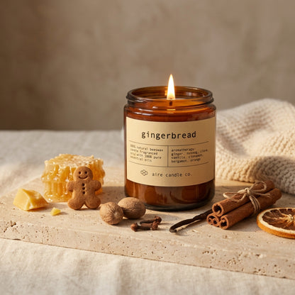 gingerbread candle by aire candle co. with natural elements and scent notes on a travertine surface.