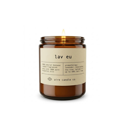 Aire Candle Co. Lav Eu Beeswax Candle Displayed with an Illuminated Flame Housed in a Protective Amber Glass Jar.
