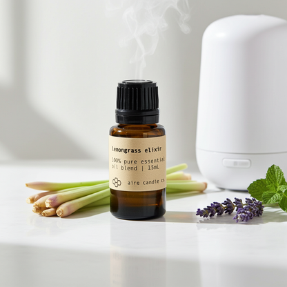 Lemongrass Elixir 100% pure essential oil blend in a 15ml amber glass bottle with black cap, styled with fresh lemongrass, lavender, mint, and a white diffuser releasing mist in a bright, modern setting.