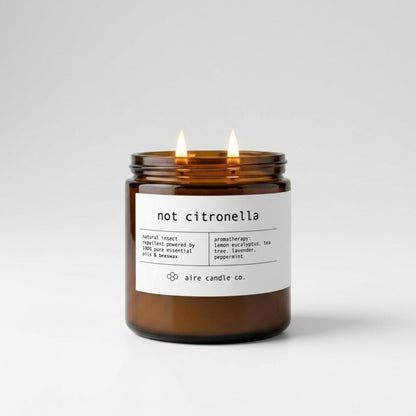 Not Citronella insect repellent candle in the 16 oz size, featuring two illuminated wicks in an amber glass vessel.