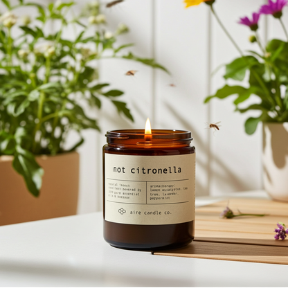 Insect repellent candle labeled 'not citronella' with plants and flowers in the background showing mosquitoes flaying away from the candle