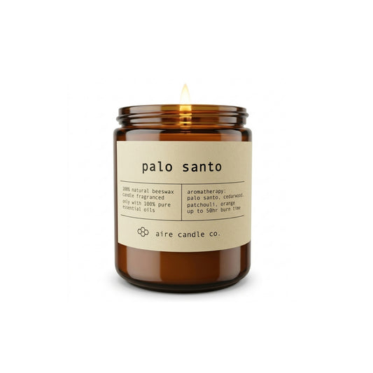 Aire Candle Co. Palo Santo Essential Oil Scented Beeswax Candle Displayed with an Illuminated Flame Housed in a Protective Amber Glass Jar.