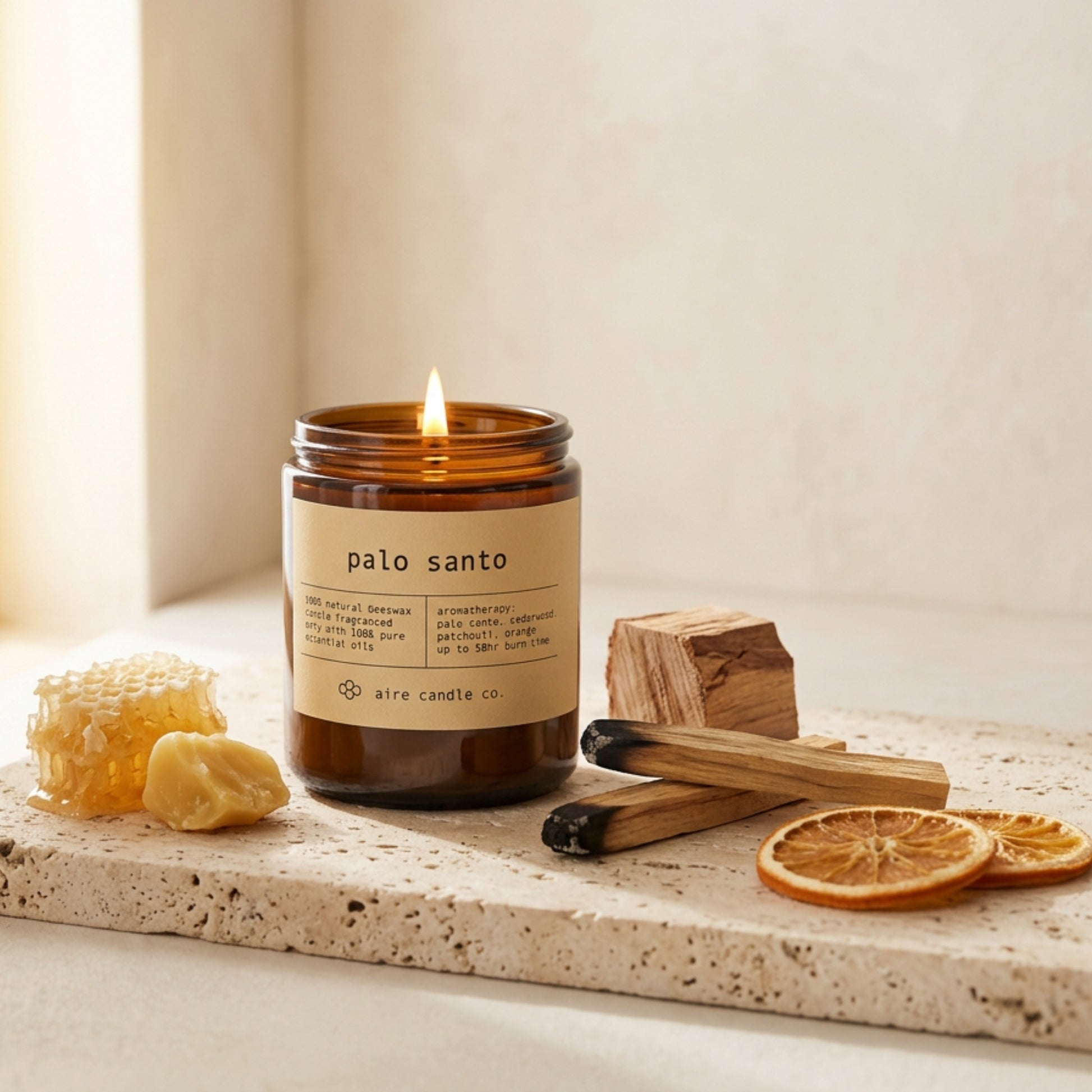 palo santo beeswax candle by aire candle co. with natural elements on a travertine surface.