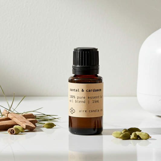 Essential oil bottle with a diffuser and sandalwood sticks and cardamom seeds on a white surface