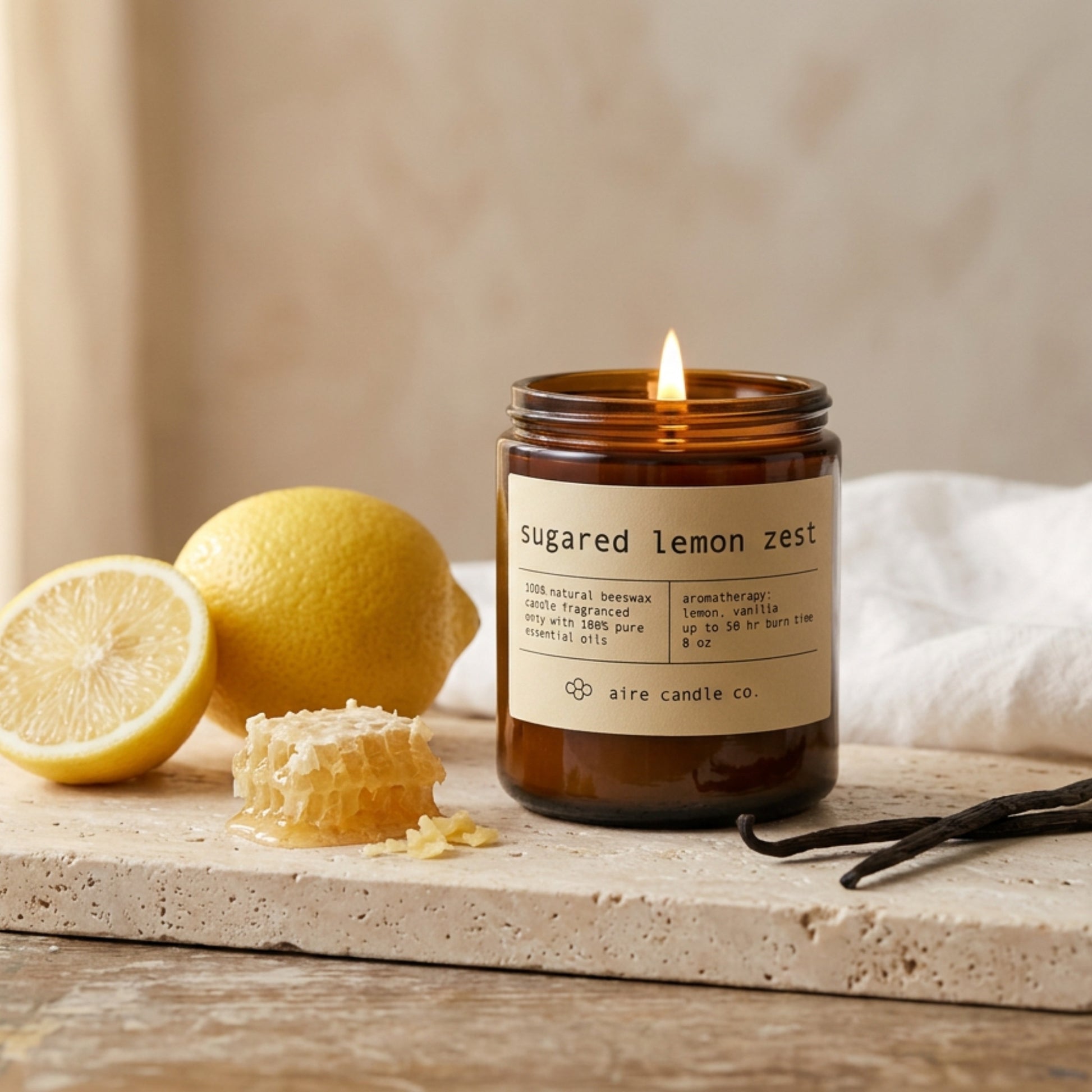 Candle labeled 'sugared lemon zest' with lemons and honeycomb on a wooden surface