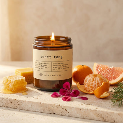 Candle labeled 'sweet tang' with fruits and honeycomb on a stone surface