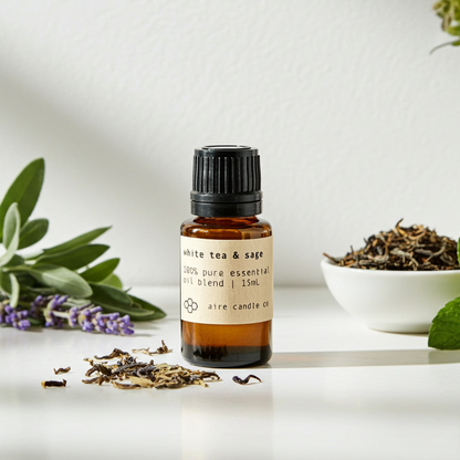Essential oil bottle labeled 'White Tea & Sage' with dried herbs and plants on a light background