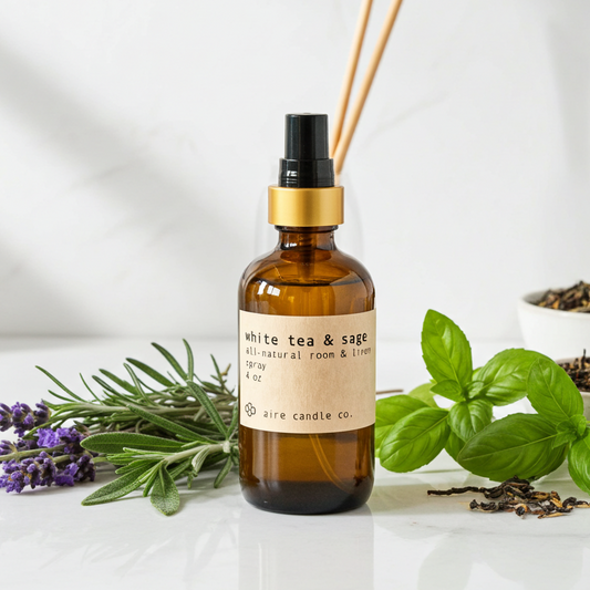 Brown bottle with gold cap labeled 'White Tea & Sage' surrounded by herbs on a white background