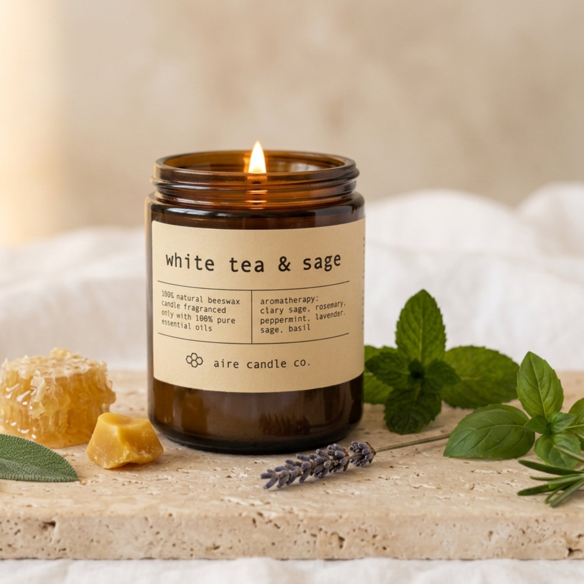 white tea & sage beeswax candle by aire candle co. with natural elements on a travertine surface.