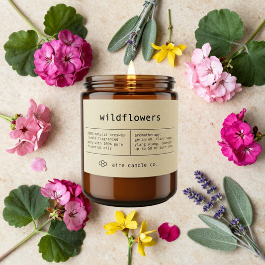 Aire Candle Co. 'Wildflowers' candle surrounded by flowers on a beige background